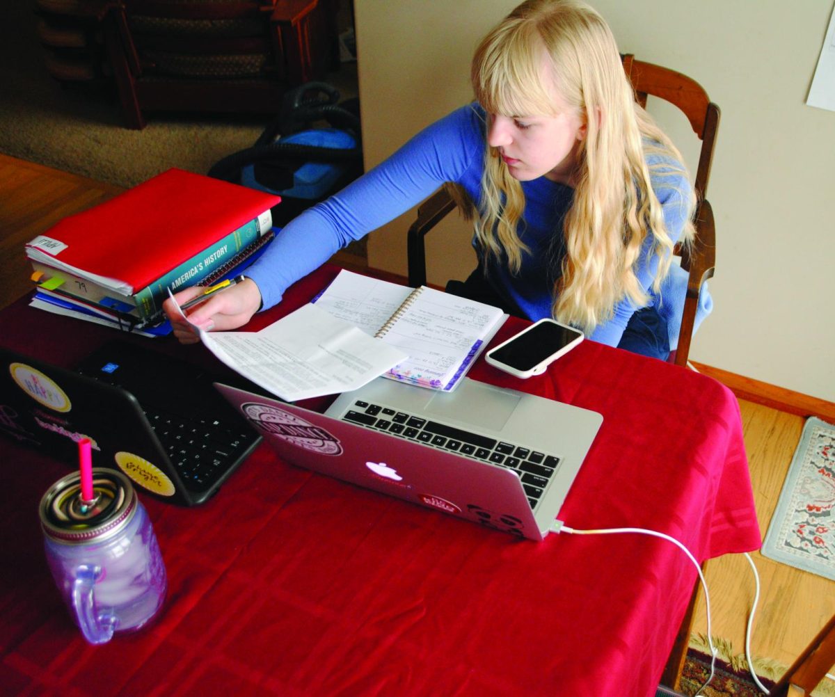 Back in her remote learning set up from first semester, junior Vivian Kaldahl completes her e-learning on Jan. 15. Kaldahl says two laptops were really ideal while on remote. “I used one for Zoom and one for Google Classroom and homework,” she said.  Photo by Christine Kaldahl