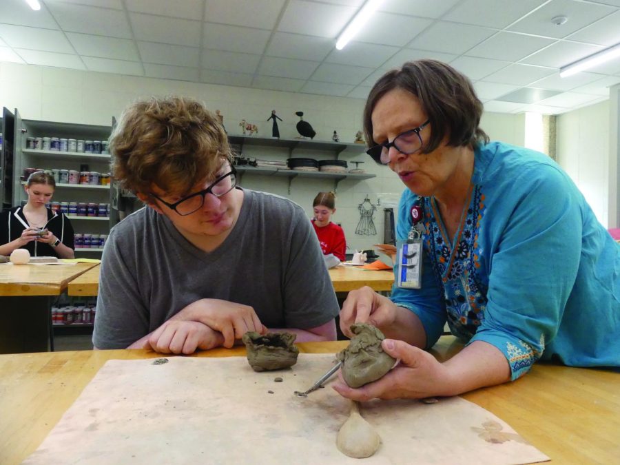 Art teacher Julia Gilreath shows junior Ethan Hopkins the kurinuki technique for carving out a container. Hopkins is in Pottery and Sculpture class.