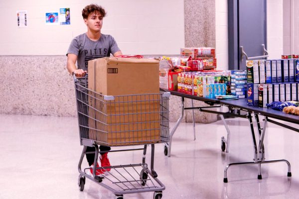 Junior and Student Council member Kolby Cameron moves goods to a a table for easy access to families coming for the special pantry night.