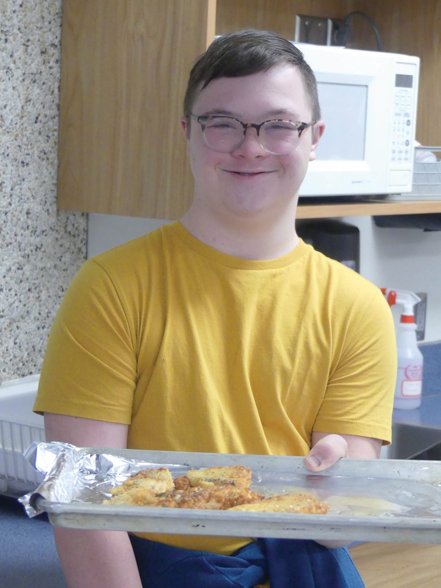 Student Vollen Schlueter serves up chicken parmesan as part of a joint cooking project in culinary skills. 