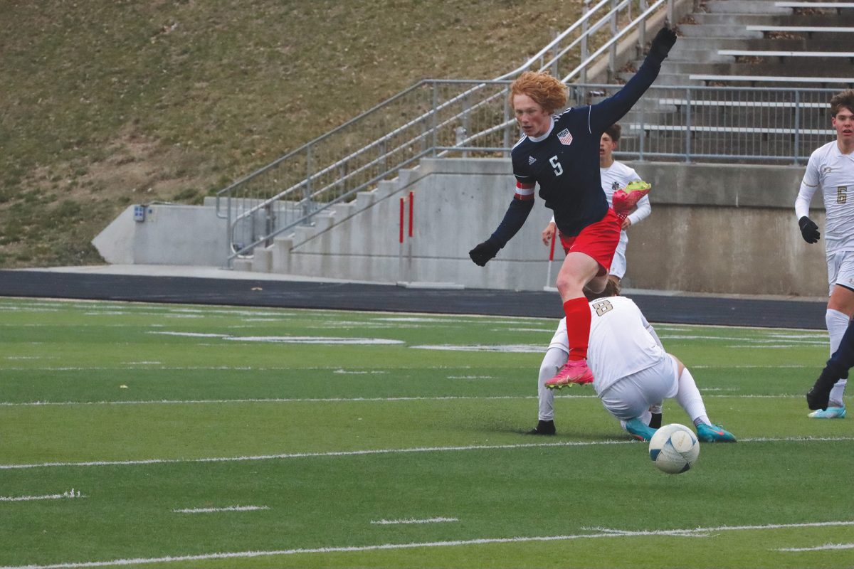 Senior Jack Carlson leaps over defender in match against Omaha Burke. The Patriots won the game 6-1.