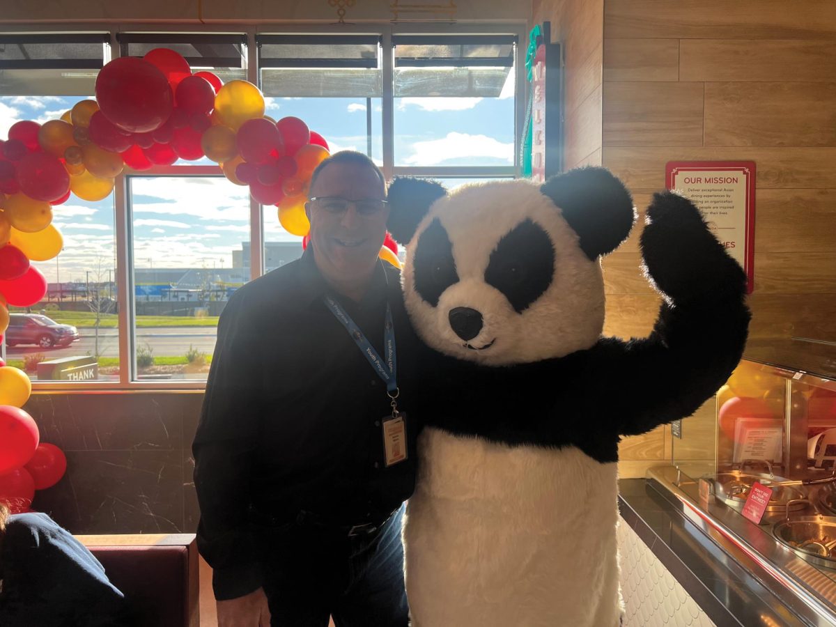 Director of Bands Darren Myers celebrates the grand opening with the Panda Express mascot.