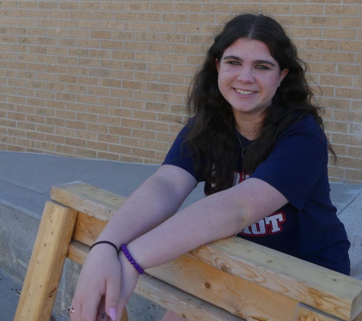 Freshman Leah Wigginton uses a saw horse as a prop near the shop area outside during the photo shoot in natural light.