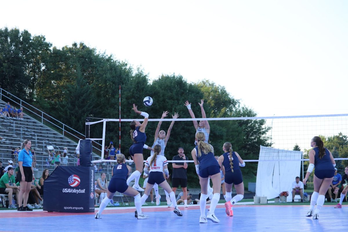 Junior Liv Koziol tries to thread the ball through two Millard West defenders. The Patriots took the 2nd set 25-14.
