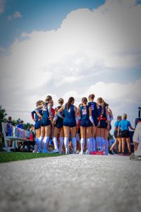 The Patriots huddle up before the first set against Millard North. This is the first time in school history the volleyball team has played an outdoor match.