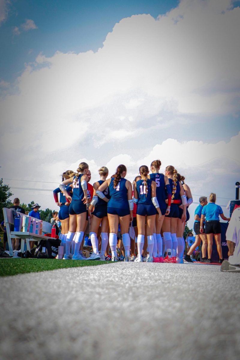 The Patriots huddle up before the first set against Millard North. This is the first time in school history the volleyball team has played an outdoor match.